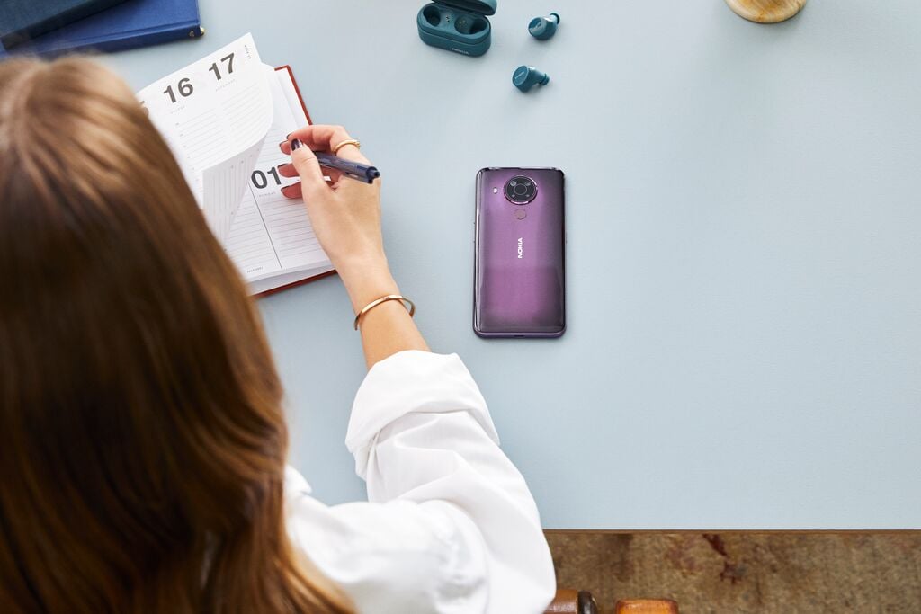 woman writing to calendar with smartphone on table