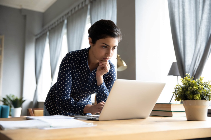 woman in polka dot shirt looking at laptop