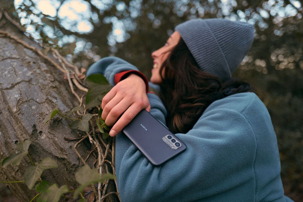 girl leaning against a tree with a phone in her hand