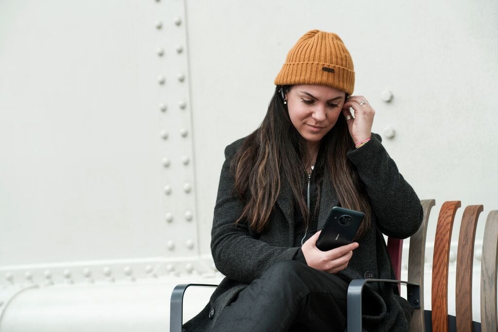 woman with beanie looking down at her phone