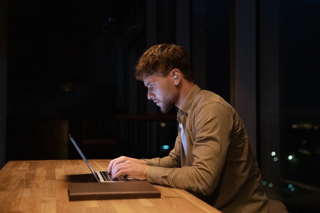 man sitting in dark room with laptop